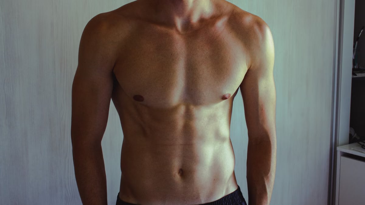 Close-up of athletic shirtless man showcasing muscular and fit physique.